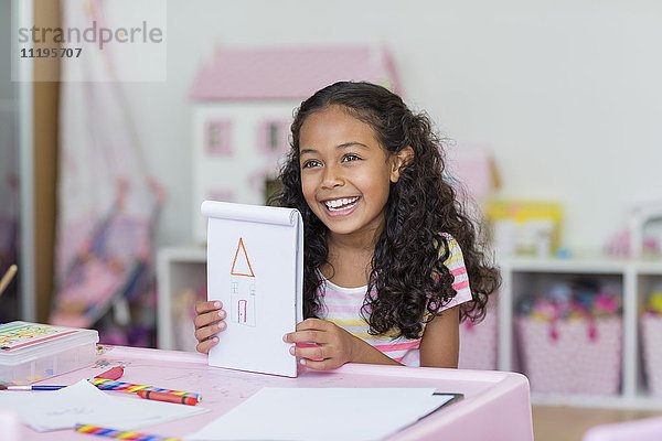 Fröhliches kleines Mädchen zeigt ihre Zeichnung
