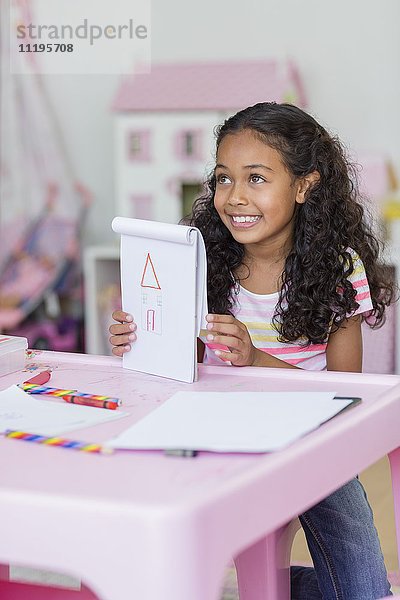 Fröhliches kleines Mädchen zeigt ihre Zeichnung