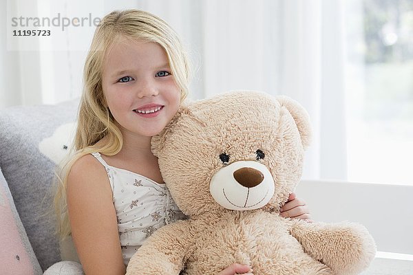 Porträt eines süßen Mädchens mit Teddybär auf dem Bett