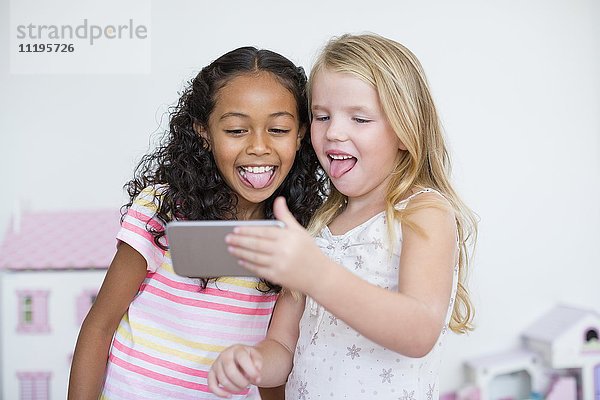 Zwei kleine Mädchen nehmen Selfie mit Fotohandy.