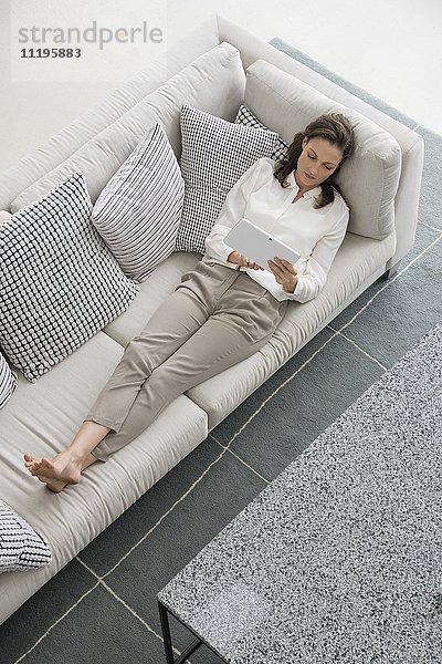 Frau auf der Couch liegend mit einem digitalen Tablett