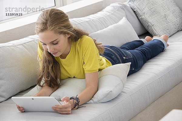 Schönes Teenagermädchen mit einem digitalen Tablett auf dem Sofa
