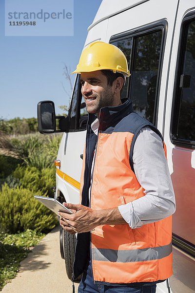 Ingenieur mit einem digitalen Tablett in der Nähe eines Lieferwagens