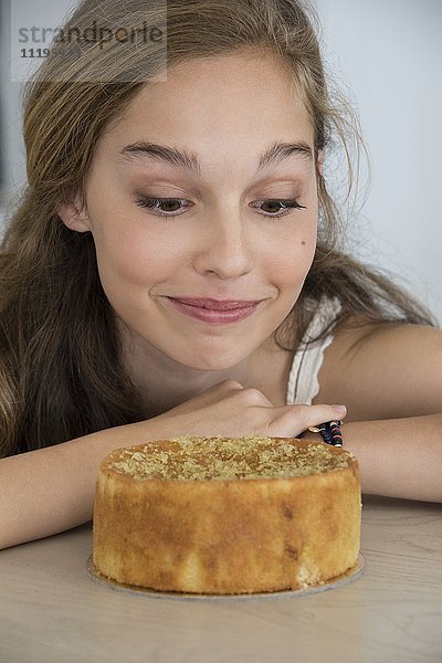Schönes Teenagermädchen schaut auf Kuchen