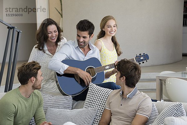 Mann spielt Gitarre für seine Freunde zu Hause