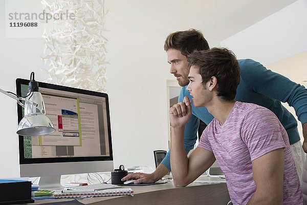 Zwei junge Geschäftsleute arbeiten zusammen am Computer in einem Büro.