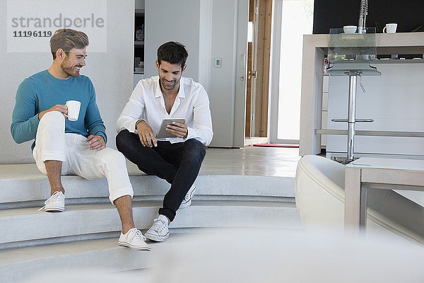 Glückliche männliche Freunde mit einem digitalen Tablett zu Hause