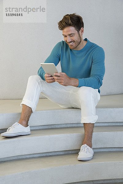 Glücklicher junger Mann mit einem digitalen Tablett zu Hause