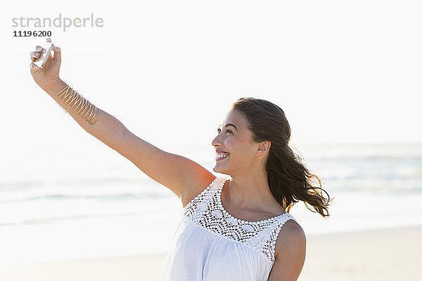 Attraktive junge Frau  die Selfie mit Smartphone am Strand nimmt