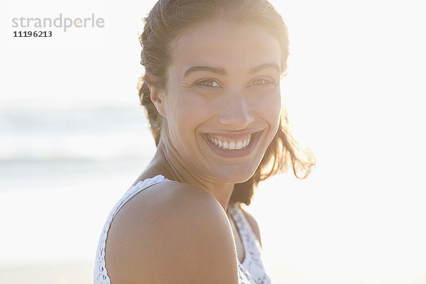 Porträt einer wunderschönen jungen Frau  die am Strand lächelt.