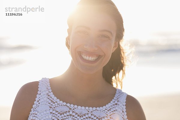 Porträt einer glücklichen jungen Frau  die am Strand lächelt