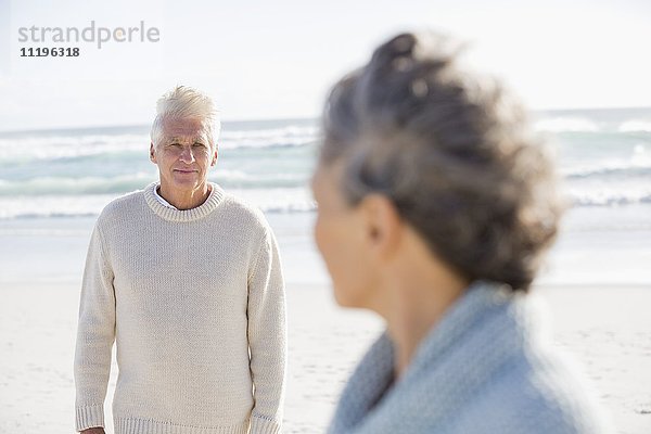 Älterer Mann schaut seine Frau am Strand an