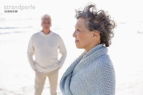 Nahaufnahme einer Frau am Strand mit ihrem Mann im Hintergrund