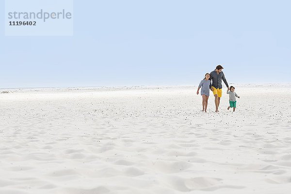 Ein Mann mit seinen Kindern am Strand.