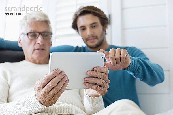 Glücklicher Vater und Sohn mit digitalem Tablett im Wohnzimmer
