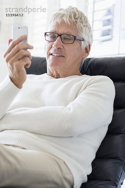 Glücklicher älterer Mann mit einem Mobiltelefon