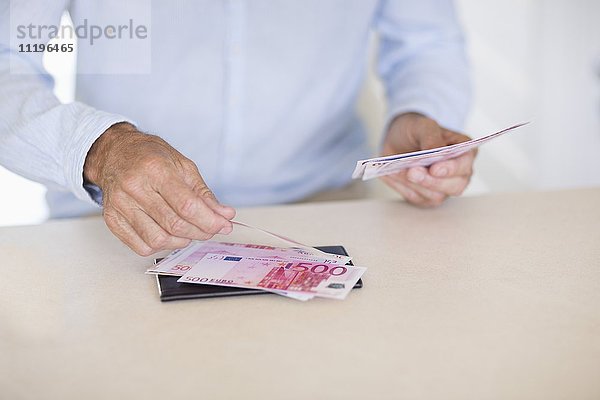 Mittelteilansicht eines älteren Mannes beim Zählen von Geldscheinen