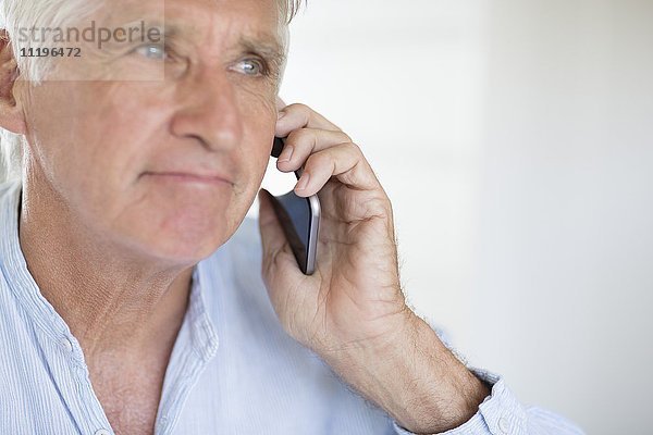 Ein älterer Mann  der auf dem Handy spricht.