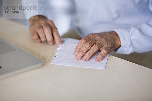Mittelteilansicht eines Seniorenöffnungsbriefes mit Laptop auf dem Tisch
