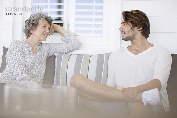 Glückliche Mutter und Sohn reden auf der Couch im Wohnzimmer