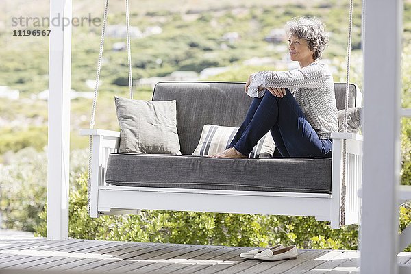 Reife Frau auf einer Schaukel in einer Veranda sitzend