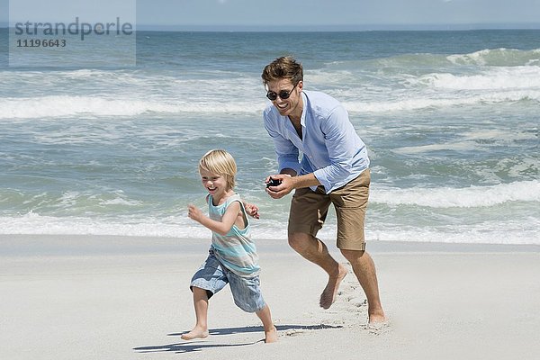 Junger Mann spielt mit seinem Sohn am Strand.