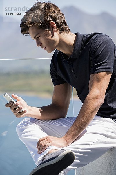 Junger Mann mit Telefon auf dem Balkon im Freien