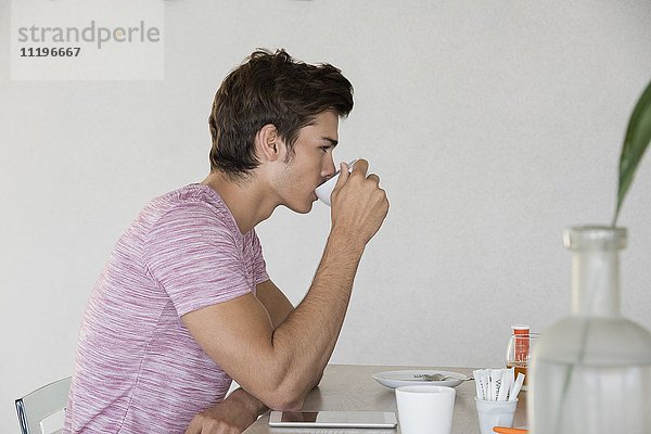 Junger Mann bei einer Tasse Kaffee zu Hause