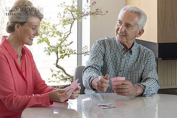 Fröhliches Seniorenpaar beim Kartenspielen zu Hause