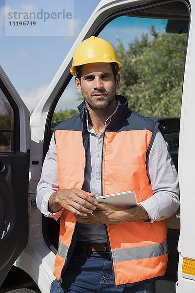Ingenieur mit einem digitalen Tablett in der Nähe eines Lieferwagens