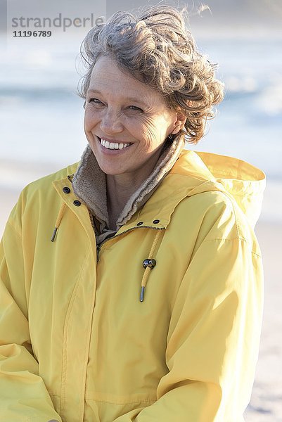 Porträt einer glücklichen reifen Frau  die am Strand lächelt.