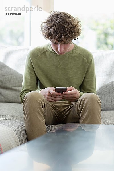 Teenager-Junge mit Telefon im Wohnzimmer