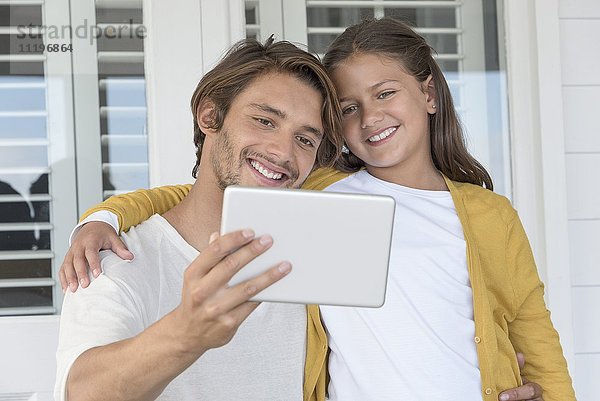 Glücklicher Vater mit seiner kleinen Tochter  die einen Selfie mit digitalem Tablett mit nach Hause nimmt.