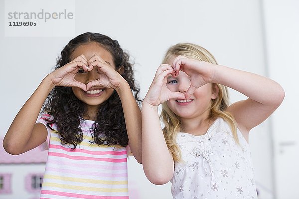Porträt von zwei kleinen Mädchen  die mit den Händen das Herz formen
