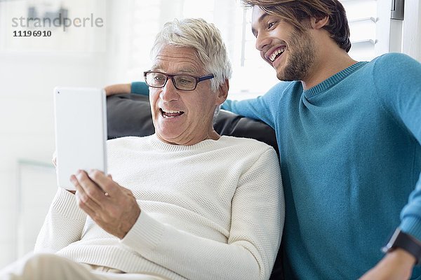 Glücklicher Vater und Sohn mit digitalem Tablett im Wohnzimmer