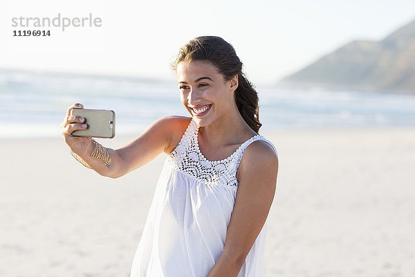 Attraktive junge Frau  die Selfie mit Smartphone am Strand nimmt
