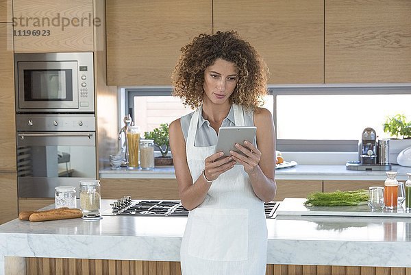 Junge Frau mit digitalem Tablett in der Küche