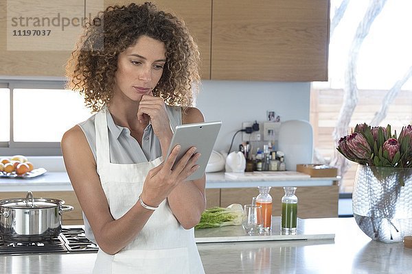 Junge Frau mit digitalem Tablett in der Küche