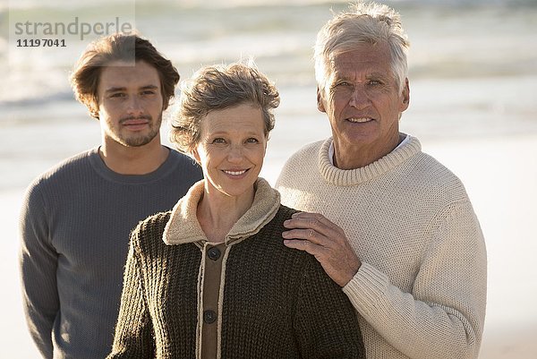 Porträt einer glücklichen Familie am Strand stehend