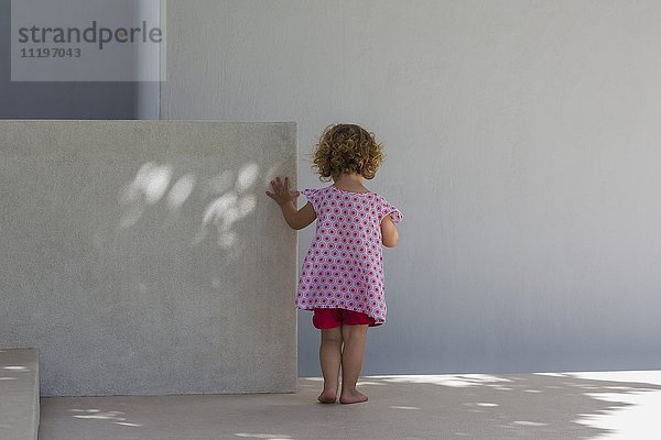 Rückansicht eines kleinen Mädchens an einer Wand stehend