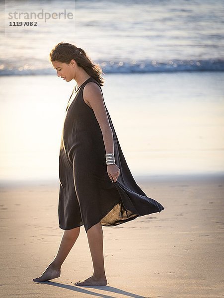 Schöne junge Frau  die am Strand spazieren geht.