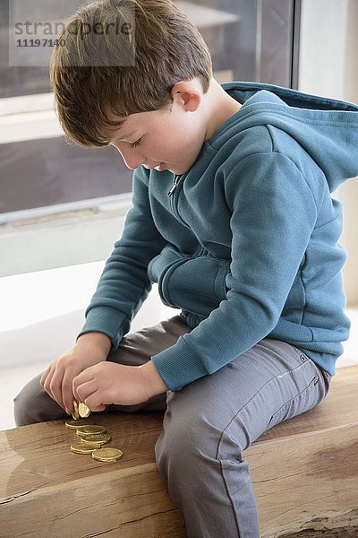 Kleiner Junge spielt mit Münzen
