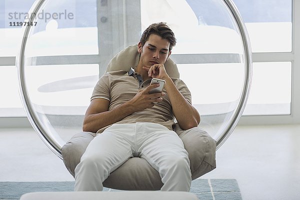 Mann auf einem Stuhl sitzend mit einem Smartphone