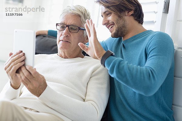 Vater und Sohn mit digitalem Tablett im Wohnzimmer