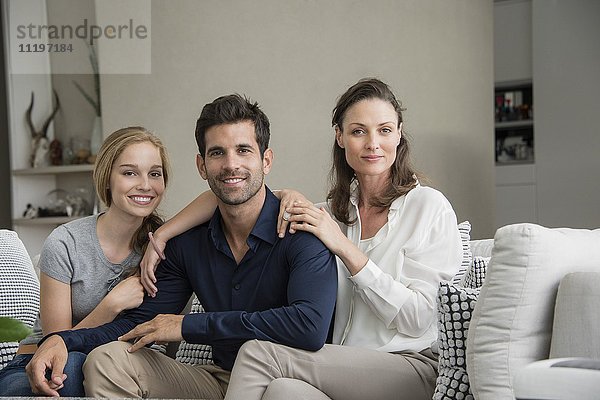 Porträt einer glücklichen Familie  die auf einer Couch sitzt.
