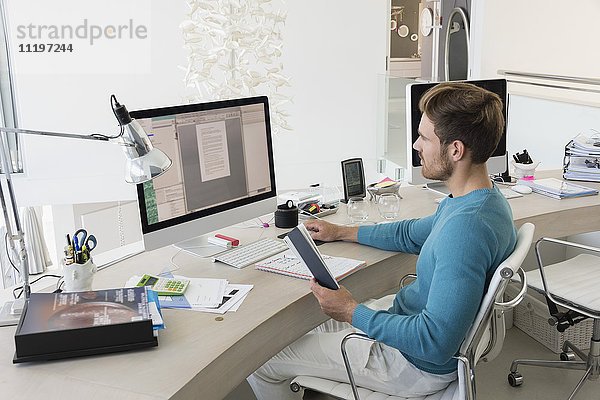 Ein junger Geschäftsmann  der in einem Büro am Computer arbeitet.