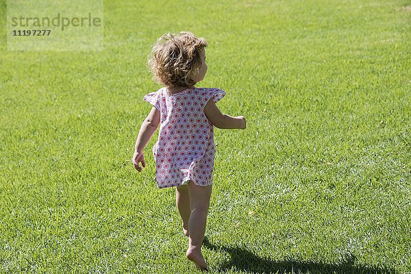 Nahaufnahme eines kleinen Mädchens  das auf dem Rasen läuft.