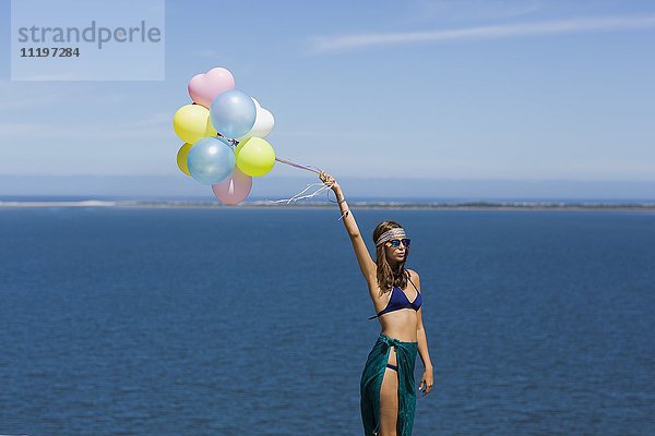 Frau mit Ballons am Meer