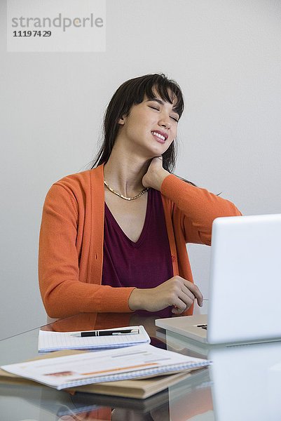 Geschäftsfrau mit Nackenschmerzen im Büro