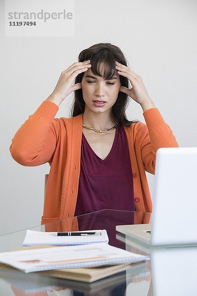 Geschäftsfrau mit Kopfschmerzen im Büro
